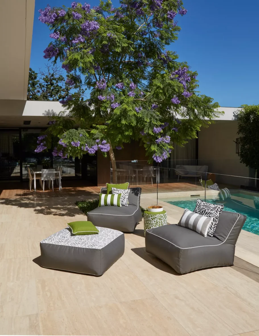 Modern outdoor seating area with gray chairs and vibrant purple flowers by a pool.