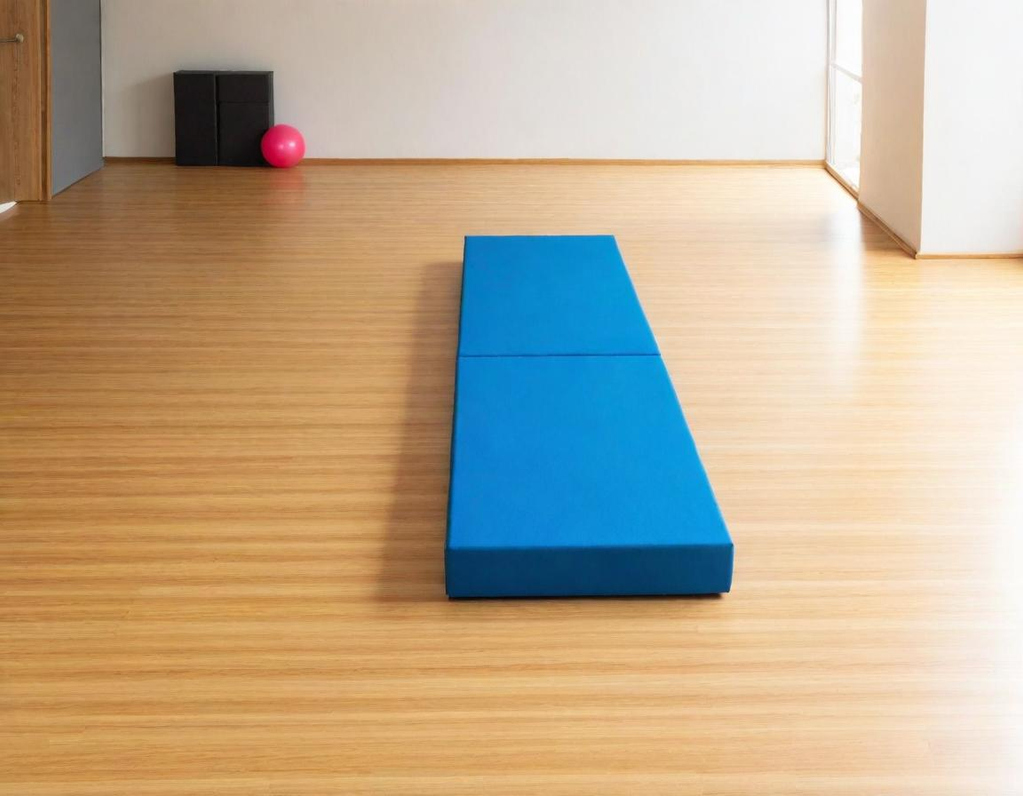 Blue gym mat placed on a wooden floor with a pink ball in the background.