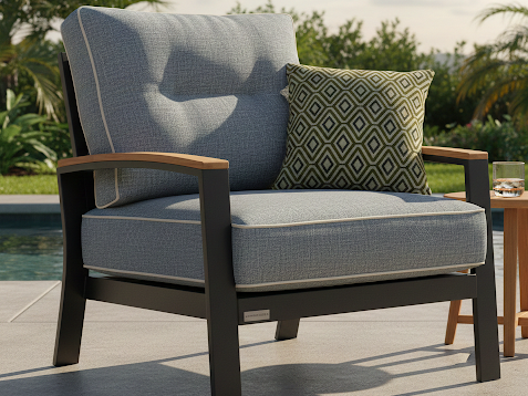 Striped lounge chair with a decorative pillow beside a small table by a pool.
