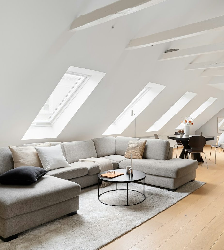 Modern living room with a gray sectional sofa, coffee table, and skylights.